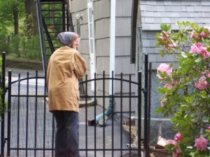 Anna at the garden gate, in coat and hooded sweatshirt. Photograph by Hanna, 9 May 2010.